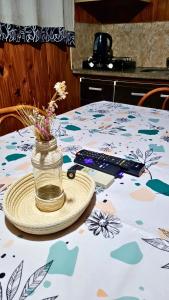 Una mesa con un mando a distancia y un tarro de flores. en El Lapacho Cabañas, en San Agustín de Valle Fértil 8 fotos más
