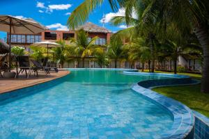 a swimming pool at a resort with palm trees at Villas BobZ Ap 110 in Barrinha
