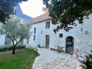 a stone house with a patio and a table and chairs at Studio Cosy dans les granges d un château accès spa in Varennes Vauzelles