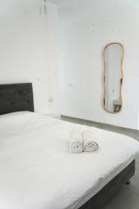 ein weißes Bett mit 2 Handtüchern und einem Spiegel in der Unterkunft Velizabeth in Omen