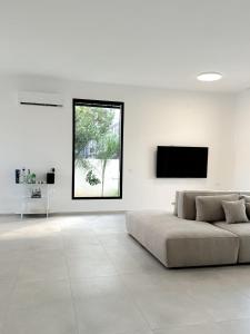 a white living room with a couch and a flat screen tv at וילת Velizabeth in Omen