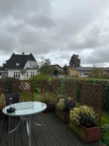 a wooden deck with a table and some flowers at Motel Villa Søndervang 3 personers værelse in Harndrup