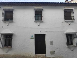 un edificio blanco con una puerta y ventanas negras en Paco del Molino 2, en Grazalema