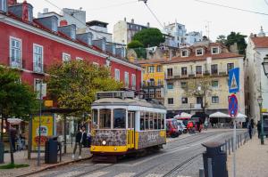 un tranvía amarillo en una calle de la ciudad con edificios en Totally Tour Portugal LDA, en Lisboa