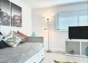 ein weißes Schlafzimmer mit einem Bett und einem Flachbild-TV in der Unterkunft GroveO1 10 min from the beach in Miami