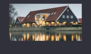 a large house sitting next to a body of water at Stelle plas231 Chalet 4 personen in Heinkensand