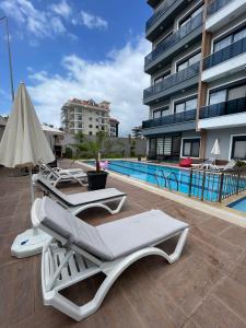 two lounge chairs and a pool in front of a building at Kestel City in Alanya +23 photos