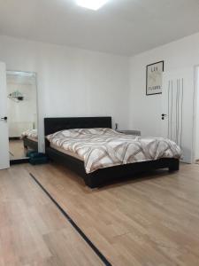 a bed in a white room with a wooden floor at Suita Brasonka in Braşov