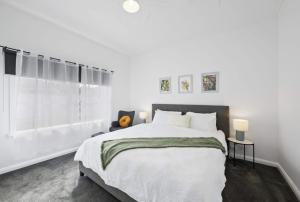 a white bedroom with a large bed and a window at Eureka We struck a golden home in Eureka