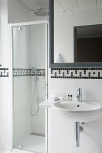 a white bathroom with a sink and a mirror at Apollon Montparnasse in Paris