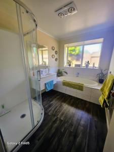 a bathroom with a shower and a tub and a sink at The Holiday Haven in Tauranga