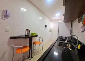 a kitchen with orange chairs and a sink and a counter at Apê da Thais in Balneário Camboriú