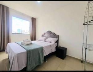 a bedroom with a bed with white sheets and a window at Apê da Thais in Balneário Camboriú