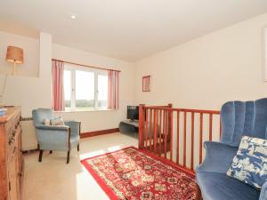 una sala de estar con un sofá y una silla en Rosewin Farmhouse, en Saint Minver