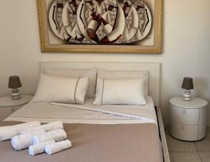a bed with white pillows and a painting on the wall at Il Mirto di Maria- La Terrazza in Fiumicino +9 photos