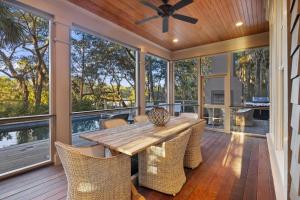 un gran porche acristalado con mesa de madera y sillas en GW09: 9 Grey Widgeon, en Kiawah Island