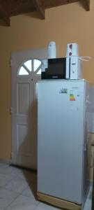 a microwave on top of a refrigerator in front of a door at La Gringa in Villa Elisa
