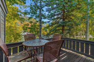 a table and chairs on a deck with trees at Evergreen Escape - Home for 12 in Mid Vail