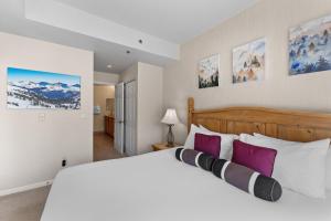 Un dormitorio con una gran cama blanca con almohadas moradas. en Greens at Copper 217 by Summit County Mountain Retreats, en Copper Mountain