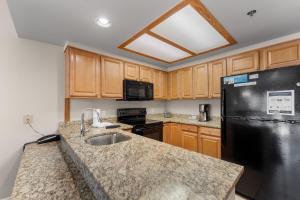 cocina con fregadero y nevera negra en Greens at Copper 217 by Summit County Mountain Retreats, en Copper Mountain