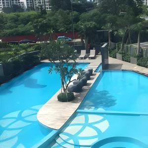 a large blue swimming pool with chairs and trees at Arvesto Jakarta in Jakarta
