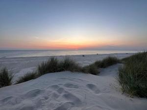 a beach with footprints in the sand at sunset at Modern Cottage by Dunes - By Traum Ferienwohnungen in Vejers Strand +30 photos