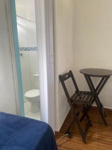 a table and a chair in a room with a toilet at Antonia Hospedaria 1 in Búzios +5 photos