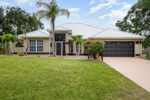 a house with a palm tree and a garage at Elegant 4BR Pool Sanctuary - Ideal for Work or Play! in Palm Bay