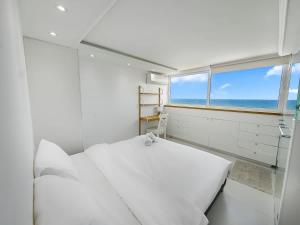 Una habitación blanca con una cama y una ventana. en Blue Horizon Penthouse, en Herzliya Pituah
