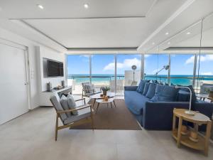 Sala de estar con sofá azul y vistas al océano en Blue Horizon Penthouse, en Herzliya Pituah