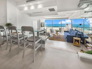 Una sala de estar con un sofá, una mesa y sillas. en Blue Horizon Penthouse, en Herzliya Pituah