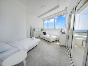 Una sala de estar con muebles blancos y vista al mar. en Blue Horizon Penthouse, en Herzliya Pituah 38 fotos más