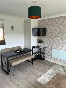 ein Wohnzimmer mit einem Tisch und einem TV an der Wand in der Unterkunft Home on the Broads Just Renovated in Lowestoft