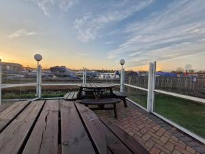 eine Holzterrasse mit einem Picknicktisch und einer Bank in der Unterkunft Home on the Broads Just Renovated in Lowestoft