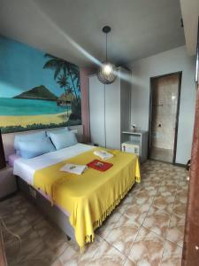 a bedroom with a large bed with a yellow blanket at POUSADA CÔCO MALUCO Centro Búzios in Búzios