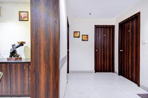 a hallway with a wooden door and a white tile floor at Super Collection O Motisarai in Kolkata