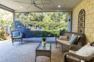 a screened porch with wicker chairs and a table at Estuary View in Geographe