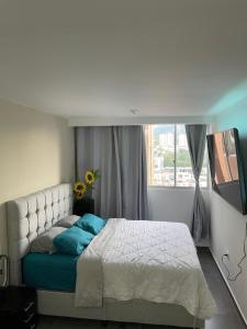 a bedroom with a bed with blue pillows and a window at Moderno Apto con Aire Acondicionado Vista a Ruitoque cerca a FOSCAL in Floridablanca
