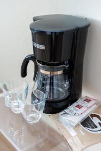 a coffee maker with two glasses on a counter at Serenity Rincon Guesthouse in Rincon