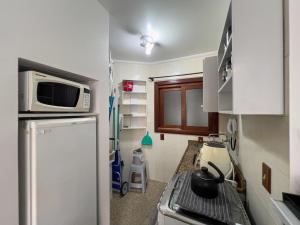 uma pequena cozinha com fogão e micro-ondas em Pé na areia em Capão da Canoa