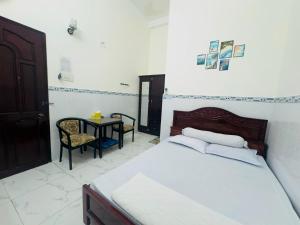 Un dormitorio con una cama y una mesa con una silla. en Khách sạn Anh Thư, en Cà Mau