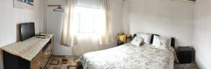 a bedroom with a bed and a television and a window at Hostal La Casa de Sandrita in Castro