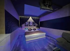 een paarse slaapkamer met een bed en een bank bij ホテルメイプル in Odate