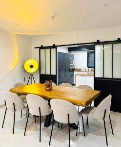 a dining room with a wooden table and white chairs at Villa design avec jardin et espaces lumineux in Seyssel