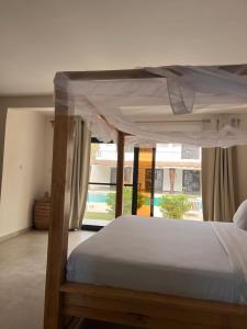a bedroom with a canopy bed and a large window at Au Paradis de Jeanne in Ngaparou +53 photos