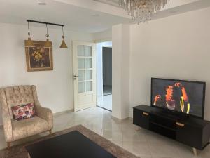 a living room with a flat screen tv and a chair at Beautiful quiet apartment in El Harrach