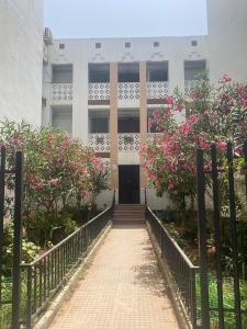 a school building with a gate and pink flowers at Beautiful quiet apartment in El Harrach
