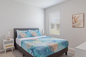 a white bedroom with a bed with a blue comforter and a window at Hot Tub Haven by Hospitals & Beach in Cape Coral