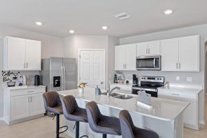 a kitchen with white cabinets and a kitchen island with chairs at Hot Tub Haven by Hospitals & Beach in Cape Coral
