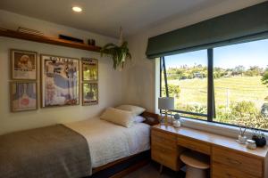 a bedroom with a bed and a window and a desk at Te Makiri House, Onetangi - Be My Guest Waiheke in Waiheke Island